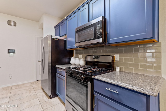 kitchen with blue cabinetry, appliances with stainless steel finishes, light stone counters, and decorative backsplash