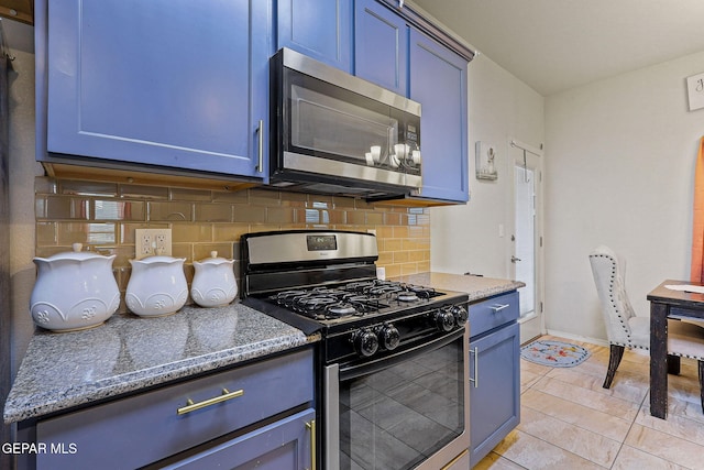 kitchen featuring blue cabinets, backsplash, stainless steel appliances, and stone countertops