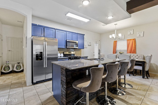 kitchen with blue cabinets, sink, a breakfast bar area, an island with sink, and stainless steel appliances