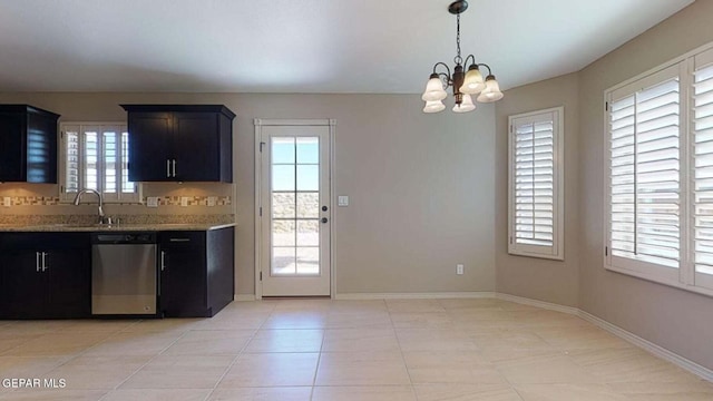 kitchen with sink, light stone counters, decorative light fixtures, stainless steel dishwasher, and a chandelier