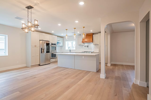 kitchen with hanging light fixtures, stainless steel appliances, a center island, and white cabinets