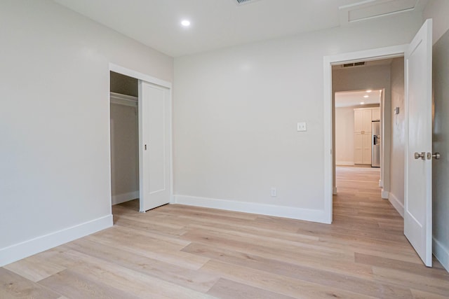 unfurnished bedroom with a closet and light hardwood / wood-style flooring