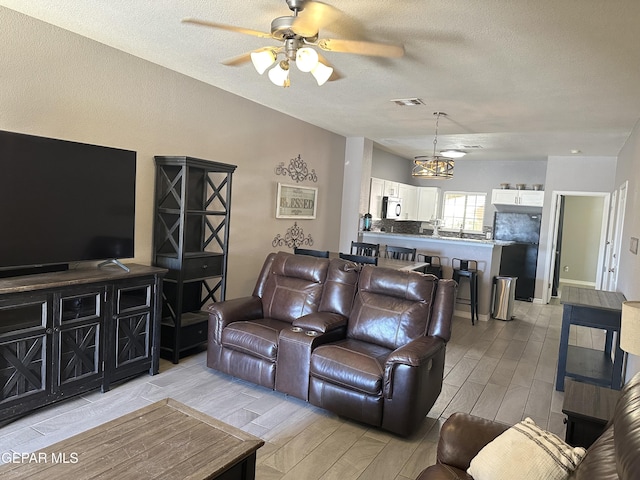 living room featuring ceiling fan and a textured ceiling