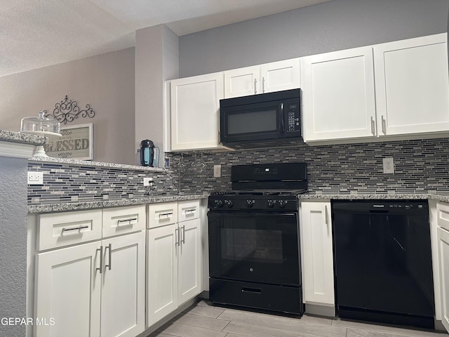 kitchen with white cabinetry, backsplash, black appliances, and light stone countertops