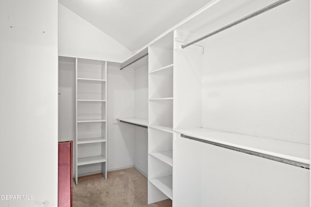 spacious closet with light colored carpet and lofted ceiling