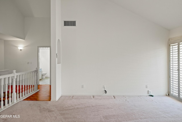 carpeted empty room featuring high vaulted ceiling