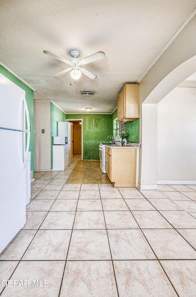 kitchen featuring light tile patterned floors, white appliances, ceiling fan, a textured ceiling, and light brown cabinets