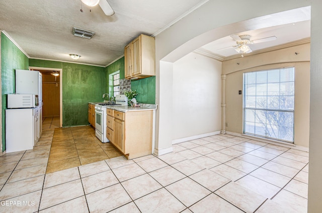 kitchen featuring light tile patterned flooring, white gas range, ornamental molding, ceiling fan, and light brown cabinets