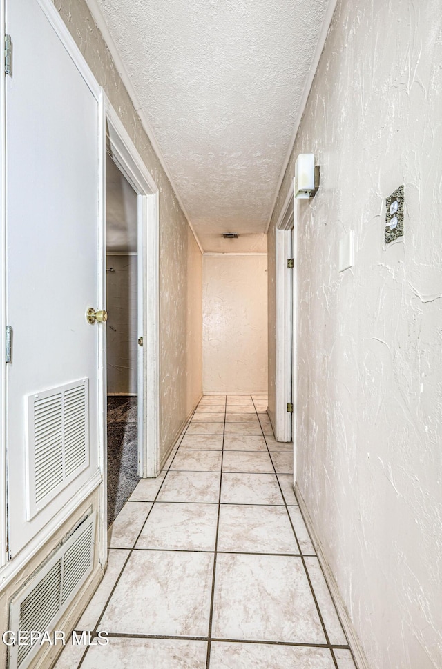 hall featuring light tile patterned floors and a textured ceiling