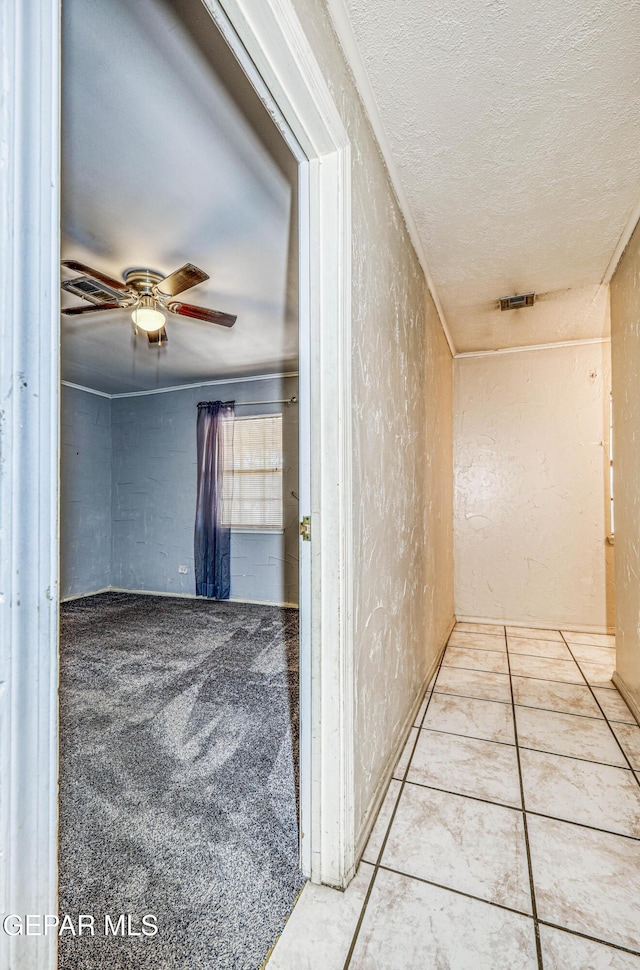 hall with a textured ceiling and light tile patterned floors