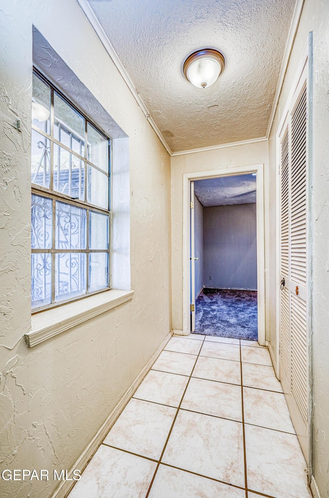 hallway with crown molding, tile patterned floors, and a textured ceiling