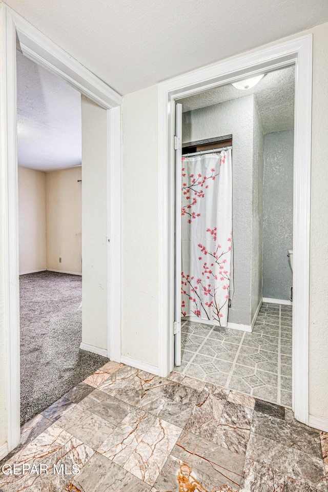 hall featuring a textured ceiling