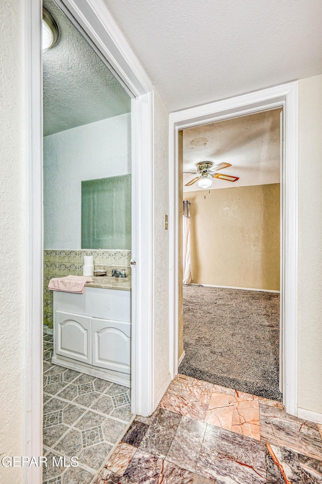 bathroom with ceiling fan and a textured ceiling