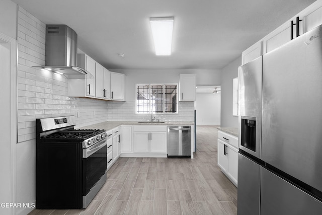 kitchen with wall chimney exhaust hood, stainless steel appliances, sink, and white cabinets