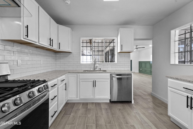 kitchen featuring sink, appliances with stainless steel finishes, light stone counters, tasteful backsplash, and white cabinets