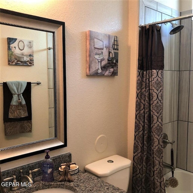 bathroom with a textured wall, a sink, and toilet