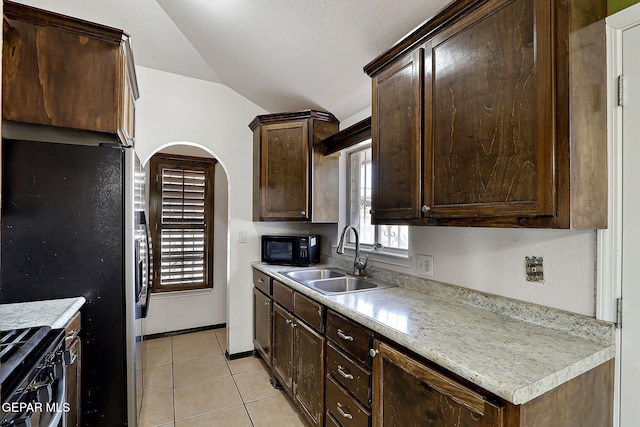 kitchen with lofted ceiling, sink, dark brown cabinetry, black appliances, and light tile patterned flooring