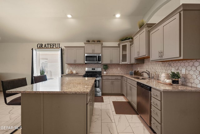 kitchen featuring gray cabinets, sink, a center island, stainless steel appliances, and light stone countertops