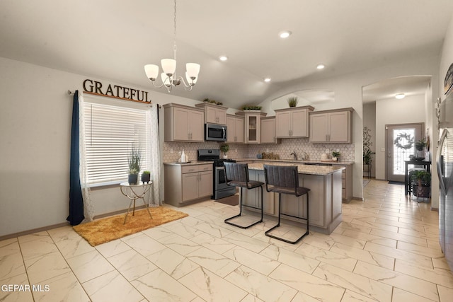 kitchen with a breakfast bar, appliances with stainless steel finishes, hanging light fixtures, tasteful backsplash, and a kitchen island