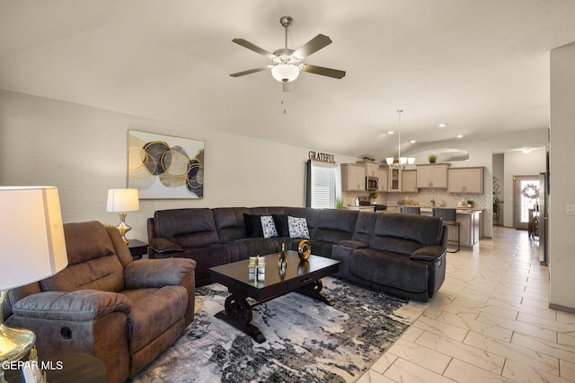 living room with lofted ceiling and ceiling fan with notable chandelier