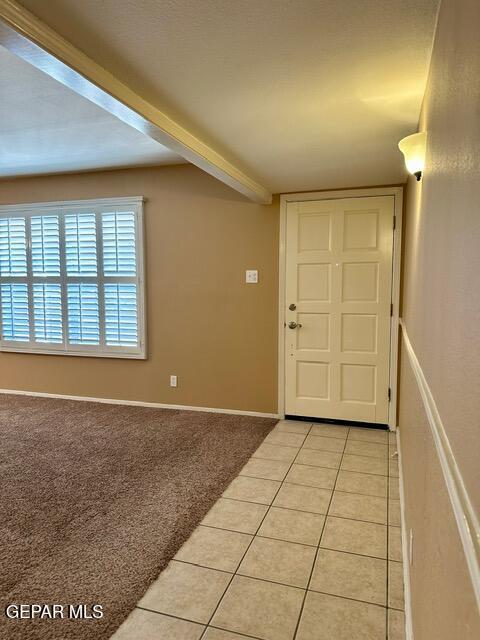 entrance foyer featuring beam ceiling and light colored carpet