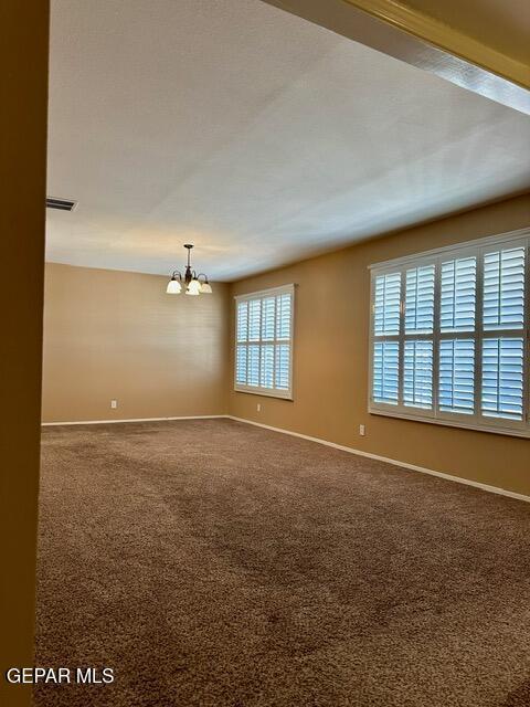 empty room with an inviting chandelier and carpet