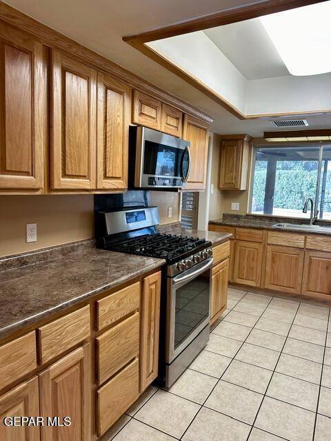 kitchen featuring stainless steel appliances, sink, and light tile patterned floors