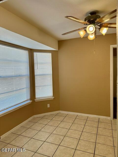 spare room with light tile patterned flooring, a wealth of natural light, and ceiling fan