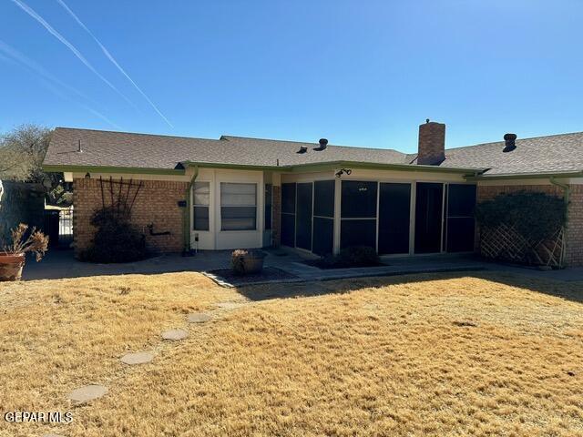 rear view of house featuring a sunroom and a lawn