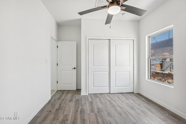 unfurnished bedroom with ceiling fan, light wood-type flooring, and a closet