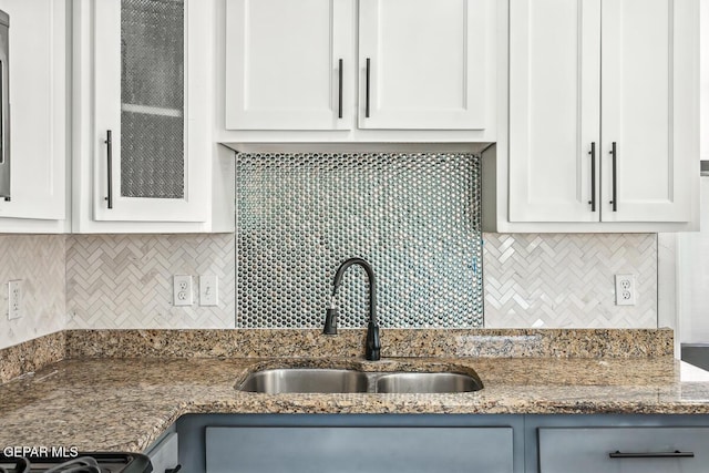 kitchen featuring sink, range, white cabinetry, dark stone countertops, and decorative backsplash