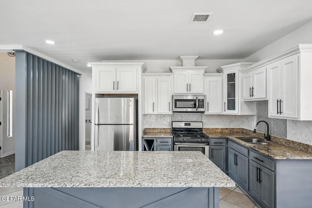 kitchen featuring sink, gray cabinetry, appliances with stainless steel finishes, decorative backsplash, and white cabinets