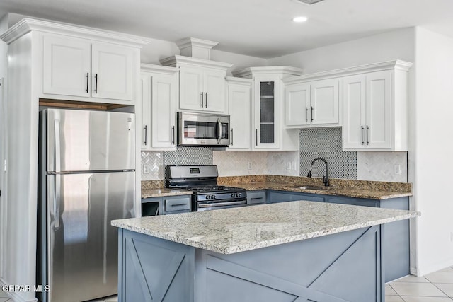 kitchen featuring a kitchen island, sink, white cabinets, decorative backsplash, and stainless steel appliances