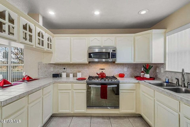 kitchen with black range with gas cooktop, sink, decorative backsplash, and light tile patterned flooring