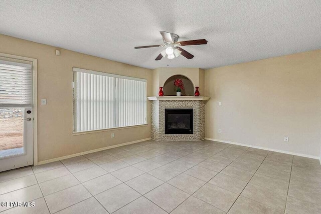 unfurnished living room with ceiling fan, light tile patterned floors, a textured ceiling, and a fireplace