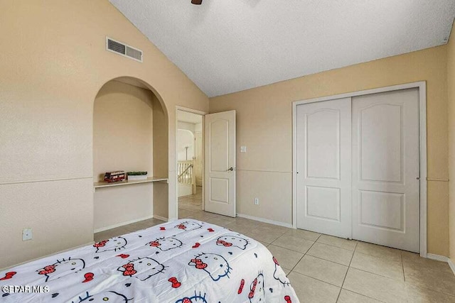 tiled bedroom with vaulted ceiling, ceiling fan, and a closet