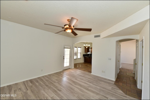 interior space featuring ceiling fan with notable chandelier, a textured ceiling, and light wood-type flooring