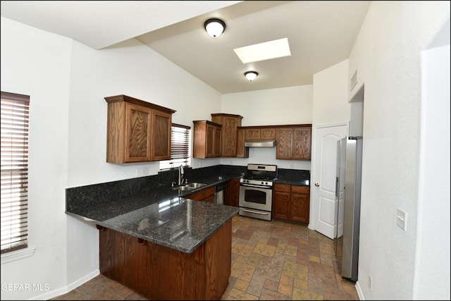 kitchen featuring sink, dark stone countertops, a skylight, stainless steel appliances, and kitchen peninsula