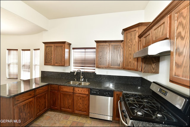 kitchen featuring appliances with stainless steel finishes, sink, kitchen peninsula, and dark stone counters