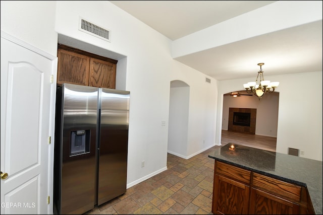 kitchen featuring a tiled fireplace, decorative light fixtures, stainless steel fridge, and a chandelier