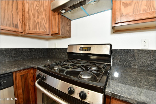 kitchen with stainless steel gas range oven, dark stone countertops, and range hood