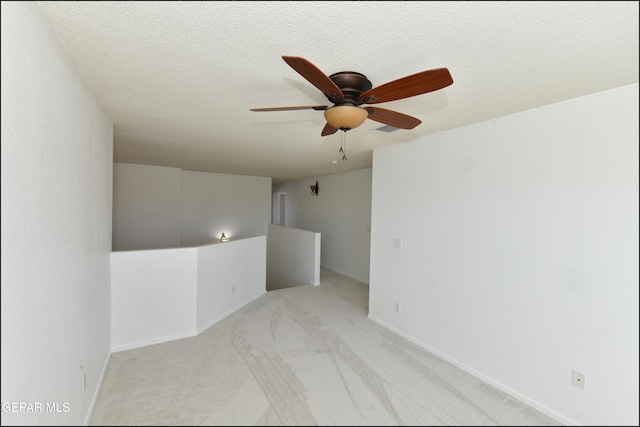 carpeted empty room featuring ceiling fan and a textured ceiling