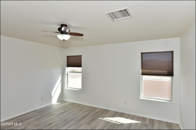 empty room featuring ceiling fan, light hardwood / wood-style flooring, and a textured ceiling