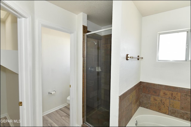 bathroom featuring toilet, independent shower and bath, and a textured ceiling