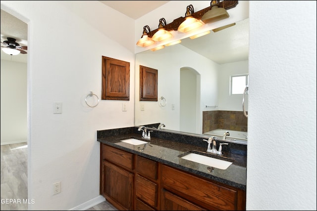 bathroom featuring ceiling fan, vanity, and a bath