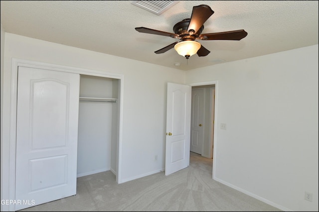 unfurnished bedroom with ceiling fan, light colored carpet, a closet, and a textured ceiling