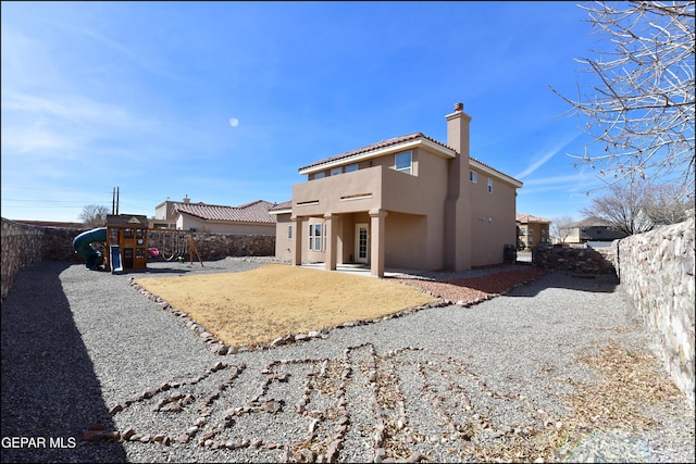 rear view of property featuring a playground and a patio area