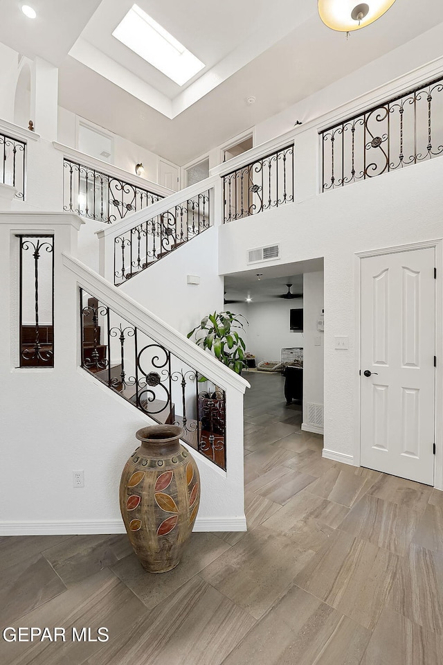 stairs with a towering ceiling and a skylight