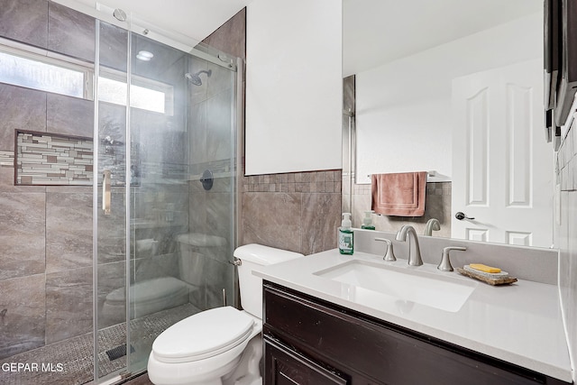 bathroom featuring tile walls, vanity, a shower with shower door, and toilet