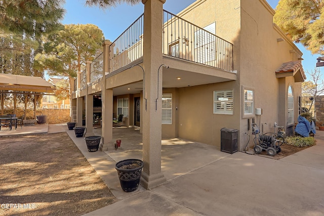 back of property featuring a balcony and a patio area